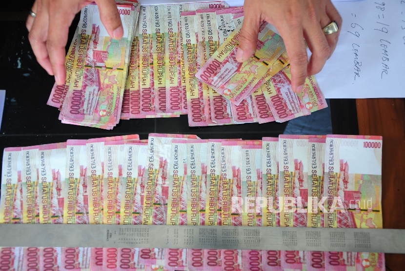 Petugas memperlihatkan barang bukti uang palsu pecahan seratus ribu rupiah.