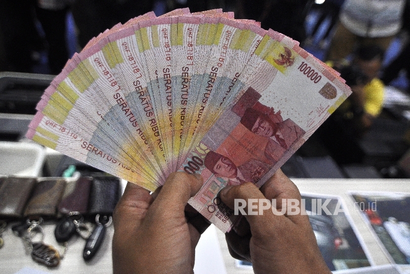 Petugas memperlihatkan barang bukti uang palsu saat rilis pengungkapan jaringan produksi dan peredaran uang palsu di gedung Bareskrim Polri, Jakarta, Rabu (18/10).
