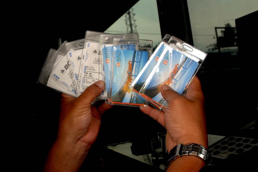 Petugas memperlihatkan e-money yang dibagikan secara cuma-cuma di gerbang pintu tol Jagorawi Citeureup, Kabupaten Bogor, Jawa Barat, Senin (16/10). 