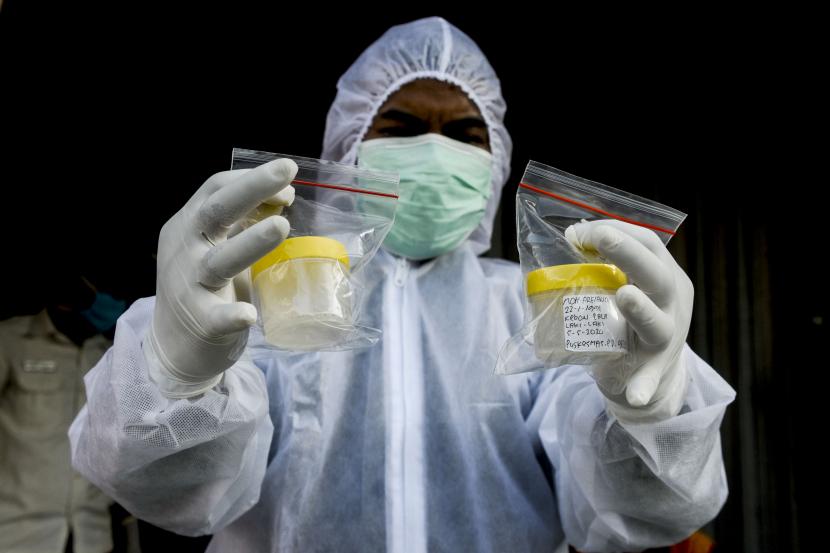 Petugas memperlihatkan wadah sampel dahak milik warga yang menjalani tes Polymerase Chain Reaction (PCR) di perbatasan Jakarta-Bekasi, Lubang Buaya, Jakarta.