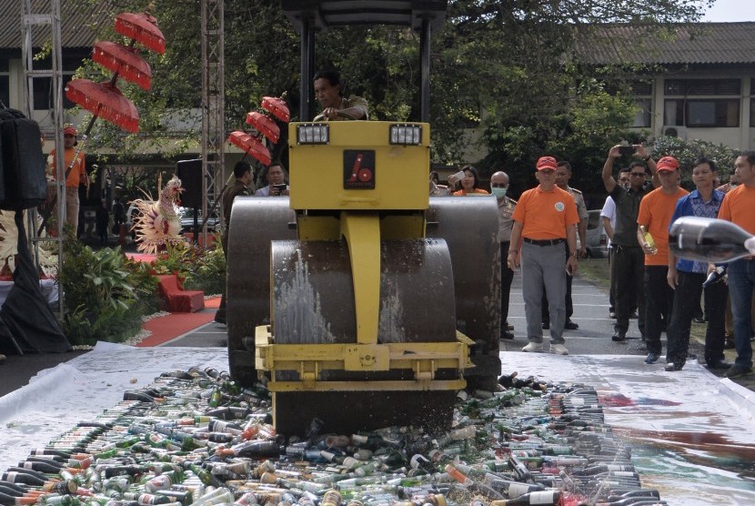 Petugas memusnahkan barang bukti miras menggunakan alat berat di Polda Bali, Denpasar, Bali, Selasa (15/8). 