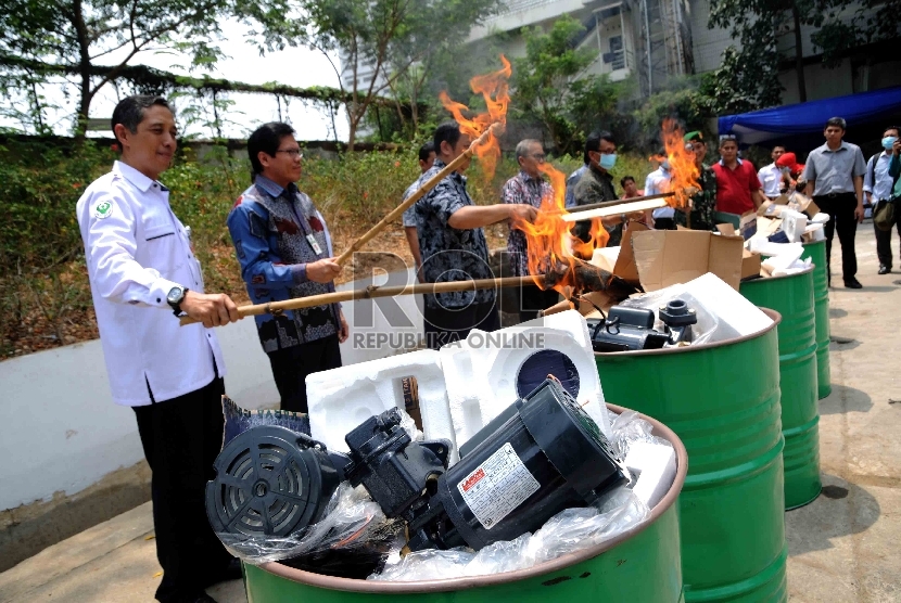 Petugas memusnahkan lampu dan pompa air listrik yang tidak sesuai Standar Nasional Indonesia (SNI) di halaman Gedung Kementerian Perdagangan, Jakarta, Kamis (29/10).