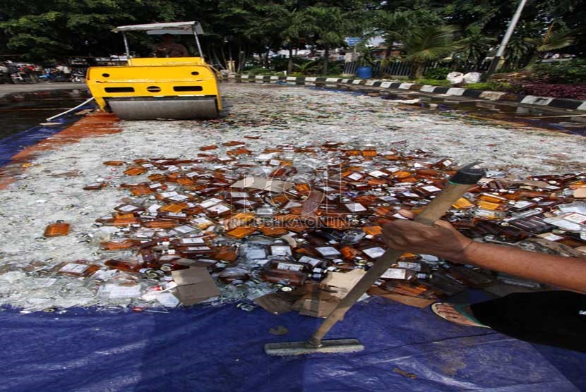   Petugas memusnahkan ratusan botol minuman keras (miras) di halaman Polsek Pulogadung, Jakarta Timur, Jumat (28/2).  (Republika/Yasin Habibi)