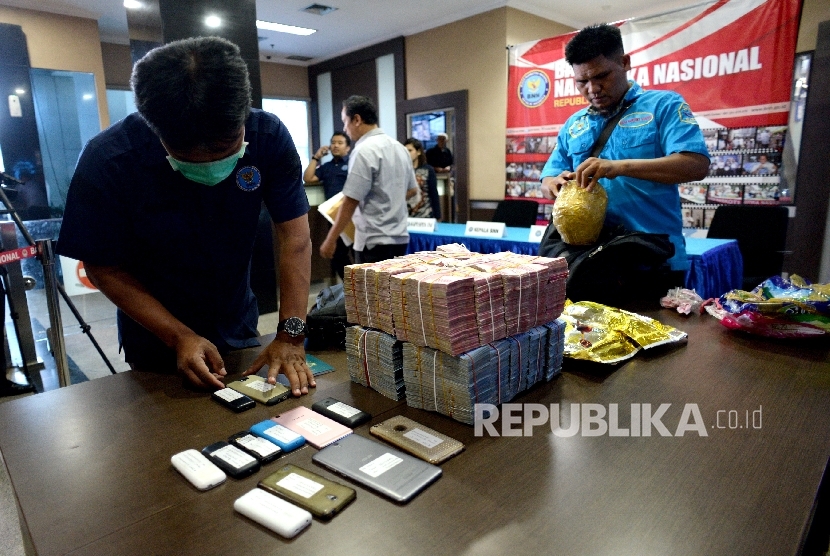 Petugas menata barang bukti uang tunai dan sabu sebelum rilis pengungkapan penyelundupan narkotia di perbatasan di BNN, Jakarta, Selasa (12/9).