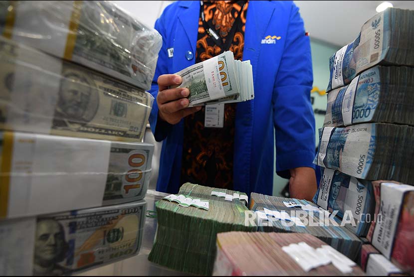 Petugas menata tumpukan uang rupiah dan dolar Amerika di Cash Center Bank Mandiri, Jakarta.