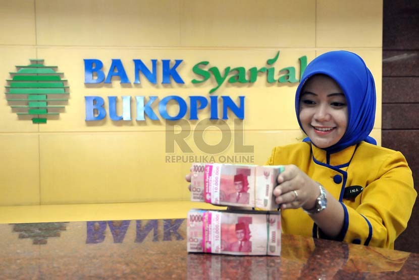 Petugas menata uang nasabah di banking hall salah satu kantor cabang Bank Syariah Bukopin, Jakarta, Senin (25/8).(Republika/Prayogi)
