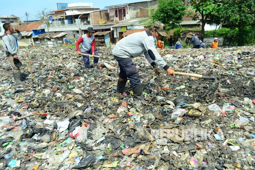 Petugas mencangkul sampah yang sudah bercampur dengan tanah di lahan kosong RT 03 RW, Kelurahan Cibangkong, Kecamatan Batununggal, Kota Bandung, Kamis (6/7)