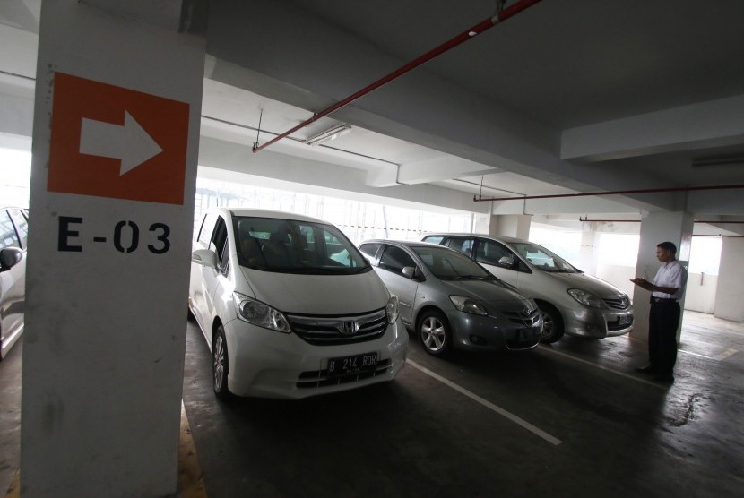 Petugas mencatat nomor polisi mobil yang terparkir di area gedung parkir Plaza Bank Mandiri, Jakarta, Jumat (11/8).