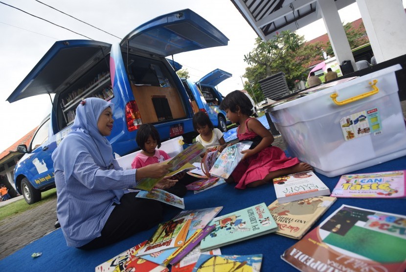 Petugas mendampingi sejumlah anak eks anggota Gerakan Fajar Nusantara (Gafatar) membaca buku di perpustakaan keliling di penampungan Asrama Transito Jawa Timur, Surabaya, Jawa Timur, Senin (25/1).