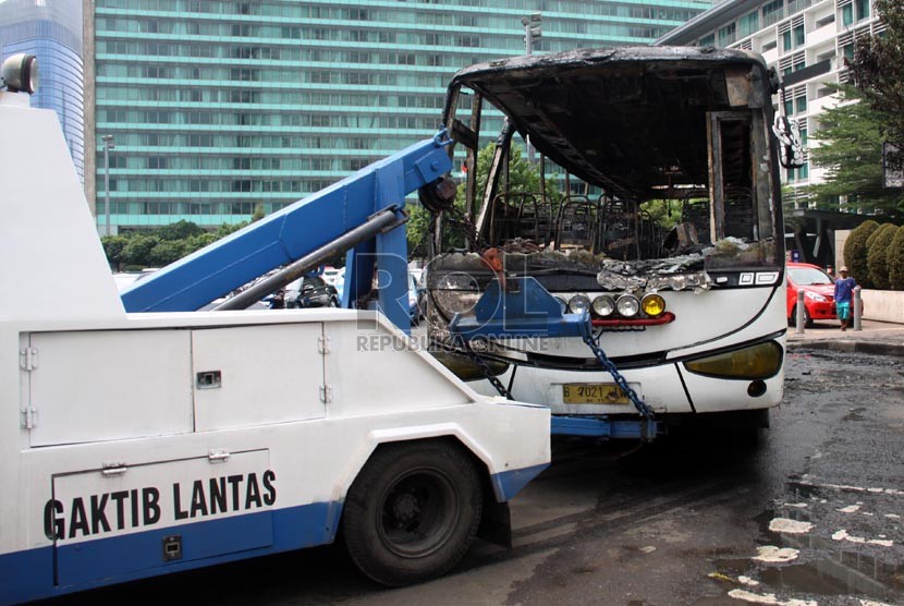 Petugas menderek bangkai bus bernopol B 7021 IW yang terbakar di kawasan Bundaran HI, Jakarta Pusat, Senin (16/12).  (Republika/Yasin Habibi)