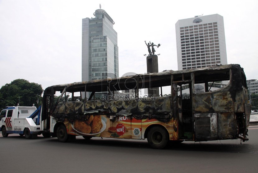 Petugas menderek bangkai bus bernopol B 7021 IW yang terbakar di kawasan Bundaran HI, Jakarta Pusat, Senin (16/12).  (Republika/Yasin Habibi)