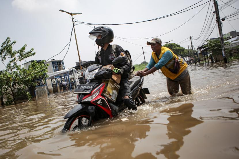 Petugas mendorong sepeda motor warga yang mogok akibat menerobos banjir di Periuk, Kota Tangerang, Banten, Rabu (11/5/2022). Hujan deras yang mengguyur sejak Selasa (10/5) malam mengakibatkan kawasan tersebut terendam banjir setinggi hingga 70 cm.
