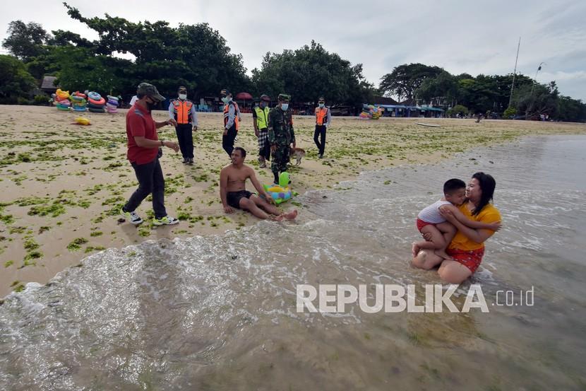 Petugas menegur warga yang beraktivitas tanpa menggunakan masker di Pantai Sanur, Denpasar, Bali. (ilustrasi)