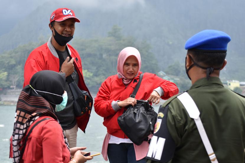 Petugas menegur wisatawan yang tidak memakai masker di kawasan wisata Telaga Sarangan, Magetan, Jawa Timur.