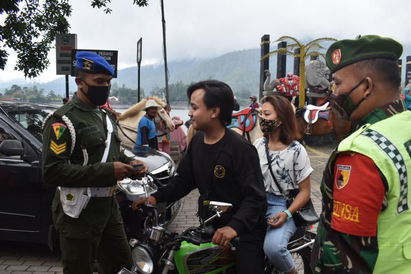 Petugas menegur wisatawan yang tidak memakai masker di kawasan wisata Telaga Sarangan, Magetan, Jawa Timur