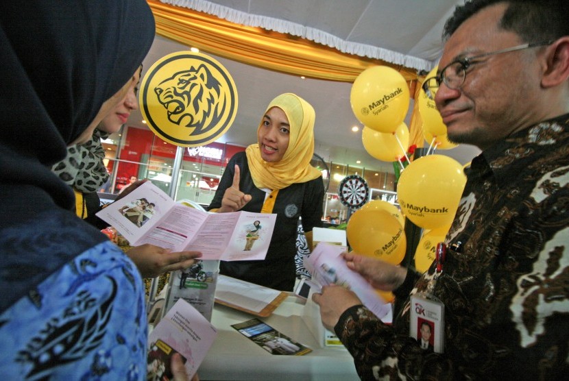 Petugas menerangkan produk perbankan syariah kepada pengunjung disaksikan Direktur Peneliti Pengembangan Pengaturan dan Perizinan Perbankan Syariah Otoritas Jasa Keuangan (OJK) Deden Firman Hendarsyah (kanan) saat 'iB Vaganza' di Kota Kediri, Jawa Timur, J