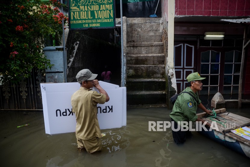 Petugas menerjang banjir saat mendistribusikan logistik keperluan Pemilu dan Pileg di Desa Bojongasih, Dayeuhkolot, Kabupaten Bandung, Jawa Barat, Selasa (16/4/2019).