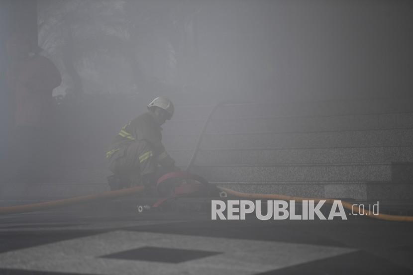 Petugas menerobos asap tebal saat berusaha memadamkan kebakaran yang terjadi di Gedung Cyber 1, Jakarta, Kamis (2/12/2021). 