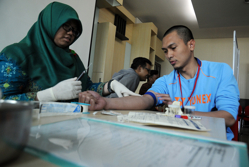 Petugas mengambil sampel darah pebulutangkis Mohammad Ahsan (kanan) saat menjalani tes medis bagi atlet Olimpiade 2016 di Rumah Sakit Olahraga Nasional, Cibubur, Jakarta Timur, Rabu (6/1).