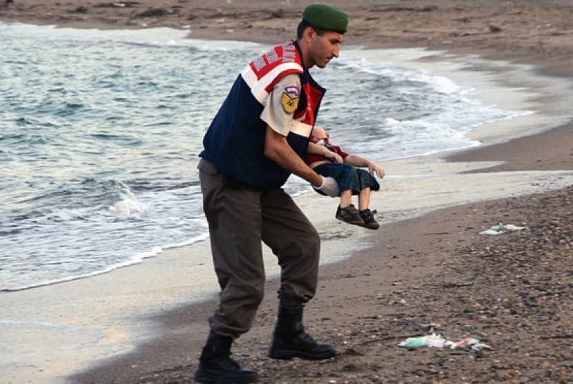 Petugas mengangkat jasad Aylan Kurdi yang tewas di pinggir laut.