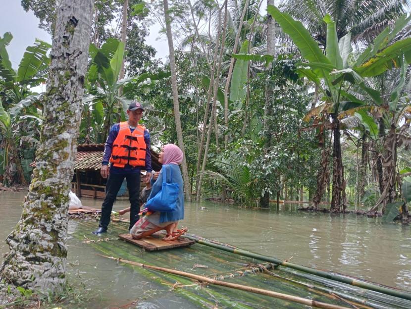 Petugas mengantarkan warga menggunakan rakit dan perahu karet di Desa Bunisari, Kecamatan Cigugur, Kabupaten Pangandaran, Selasa (27/9/2022). Akses jalan desa di wilayah itu tergenang banjir hingga 3 meter, sehingga terdapat ratusan warga yang terisolasi. 