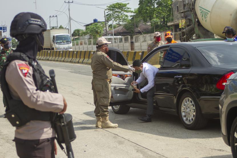 Petugas mengarahkan penumpang kendaraan roda empat untuk melakukan pembatasan sosial atau physical distancing di titik pemeriksaan di Gerbang tol Karawang Barat, Karawang, Jawa Barat, Rabu (6/5/2020). Petugas gabungan memperketat akses keluar masuk kendaraan yang akan melewati gerbang tol pada hari pertama pemberlakuan Pembatasan Sosial Berskala Besar (PSBB) di Karawang. 