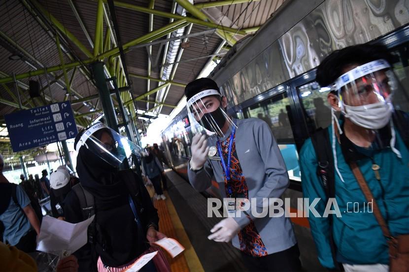 Petugas mengarahkan penumpang untuk menuju kereta api Mutiara Selatan di Stasiun Gambir, Jakarta Pusat, Kamis (30/7/2020). Epidemiolog menyebut, belum ada laporan klaster penyebaran Covid-19 di transportasi umum. 