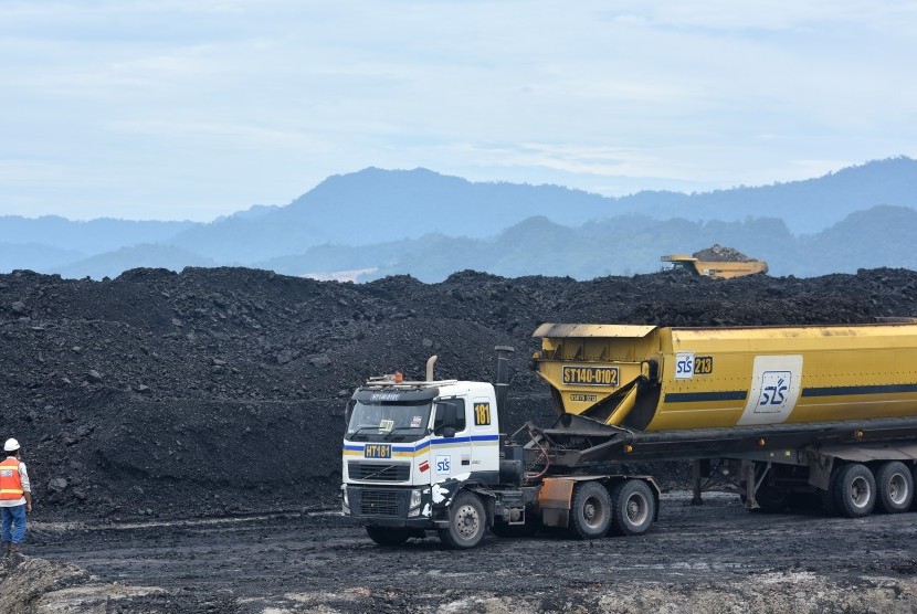 Petugas mengarahkan truk untuk bongkar muat batubara di area pertambangan PT Adaro Indonesia di Tabalong, Kalimantan Selatan, Selasa (17/10). 