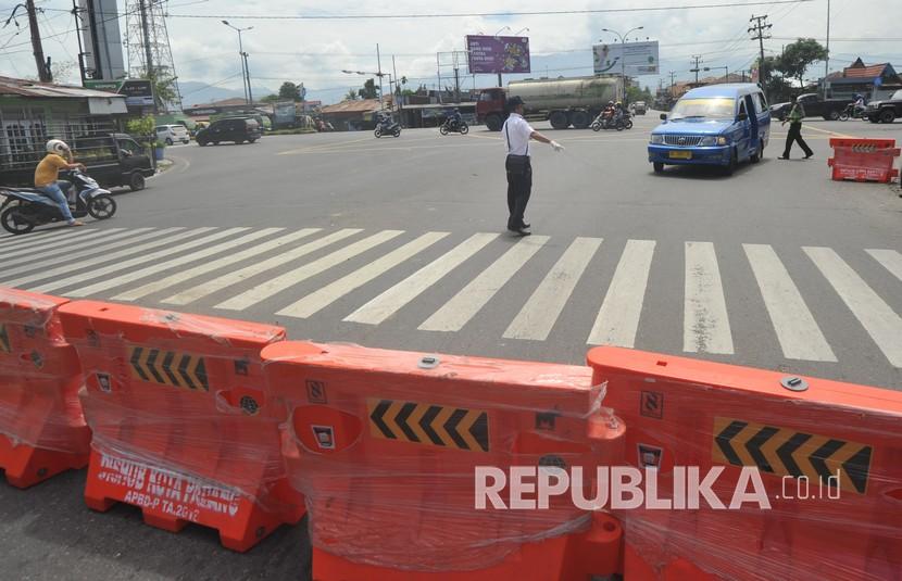 Petugas mengatur kendaraan untuk tidak masuk pusat kota, di Simpang Lubeg, Padang, Sumatera Barat, Jumat (3/4/2020). Pemkot Padang melakukan pembatasan akses masuk bagi kendaraan ke Kota Padang kecuali kendaraan membawa logistik, BBM, angkutan kota, dan roda dua untuk menekan penyebaran COVID-19 yang semakin meningkat di kota itu.