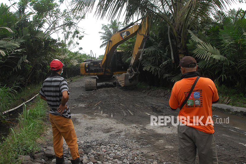 Petugas mengawasi ekskavator yang tengah melakukan perbaikan jalur evakuasi di kawasan lereng Gunung Merapi Desa Kaliurang, Srumbung, Magelang, Jawa Tengah, Senin (21/5).
