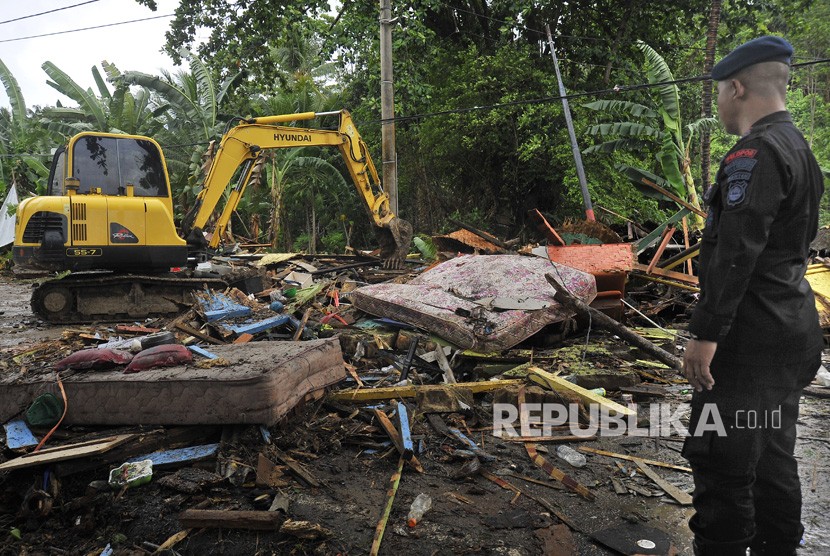 Petugas mengawasi operator alat berat membersihkan tumpukan sampah yang porak poranda menutupi jalan setelah diterjang tsunami di Pantai Carita, Pandeglang, Banten, Ahad (23/12/2018). 