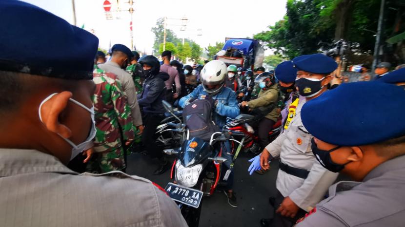 Petugas mengecek kartu tanda indetitas ataupun surat penugasan para pengendara di titik penyekatan PPKM Darurat di Jalan Daan Mogot, Kalideres, Jakarta Barat, Selasa (6/7)