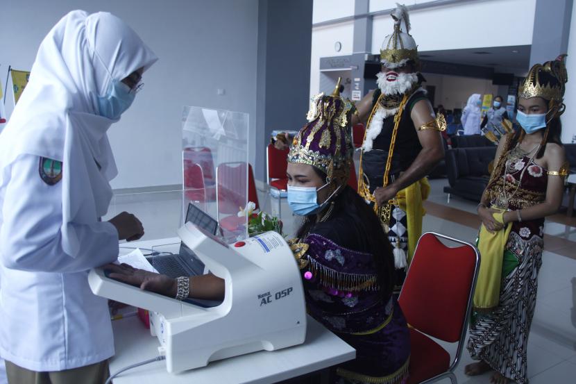 Petugas mengecek kondisi kesehatan penerima vaksin COVID-19 Sinovac berkostum tokoh wayang orang saat vaksinasi COVID-19 tahap kedua di Rumah Sakit Umum Daerah (RSUD) Bung Karno, Solo, Jawa Tengah, Jumat (5/2/2021). Penggunaan kostum tokoh wayang orang tersebut sebagai kampanye dukungan terhadap program vaksinasi COVID-19 dari pemerintah