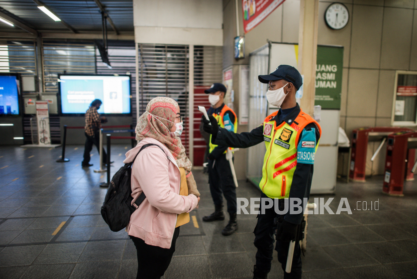 Petugas mengecek suhu tubuh calon penumpang KRL di Stasiun Manggarai, Jakarta.