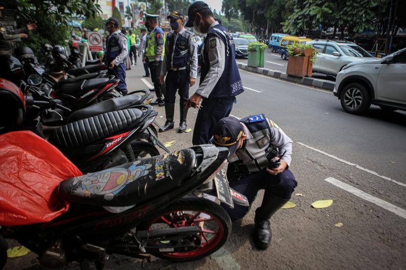 Petugas mengempiskan ban sepeda motor di lokasi parkir liar di Jalan Perintis Kemerdekaan, Kota Tangerang, Banten, Senin (22/8/2022). 