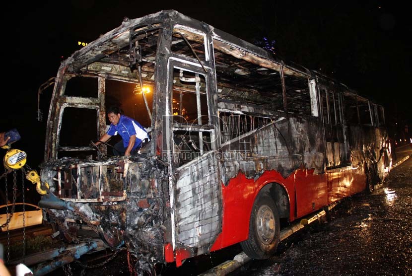  Petugas mengevakuasi bangkai Bus Transjakarta jurusan Blok M-Kota yang terbakar di Jl Jenderal Sudirman, tepat di bawah jembatan Semanggi, Jakarta, Senin (5/11) malam. (Yasin Habibi)