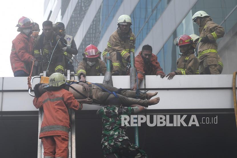 Petugas mengevakuasi korban kebakaran yang terjadi di Gedung Cyber 1, Jakarta, Kamis (2/12/2021). 