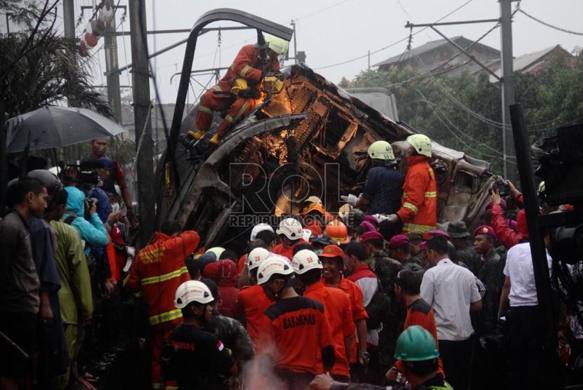 Petugas mengevakuasi korban kecelakaan kereta rel listrik di perlintasan kereta di Bintaro Permai, Tangerang Selatan, Senin (9/12). (Republika/Yasin Habibi)