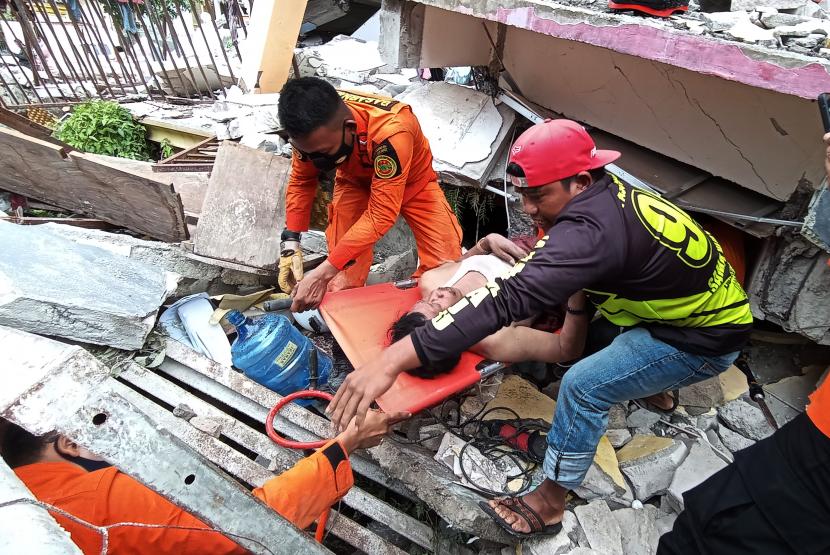 Petugas mengevakuasi korban yang terjepit bangunan di rumah sakit Mitra Manakarra yang runtuh akibat gempa bumi di Mamuju, Sulawesi Barat, Jumat (15/1)