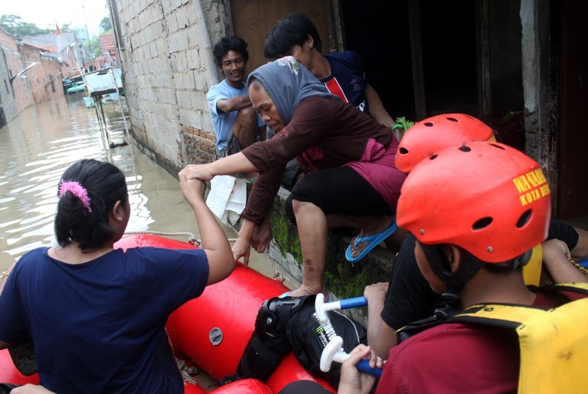 Petugas mengevakuasi sejumlah warga dengan perahu karet saat banjir merendam kawasan penduduk Kartini, Margahayu, Bekasi, Jawa Barat, Minggu (28/2).