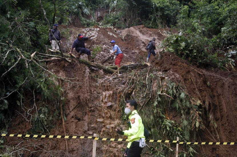 Petugas mengevakuasi tanah longsor di pinggir jalan utama Puncak, Gunung Mas, Cisarua, Kabupaten Bogor, Jawa Barat, Senin (11/1).
