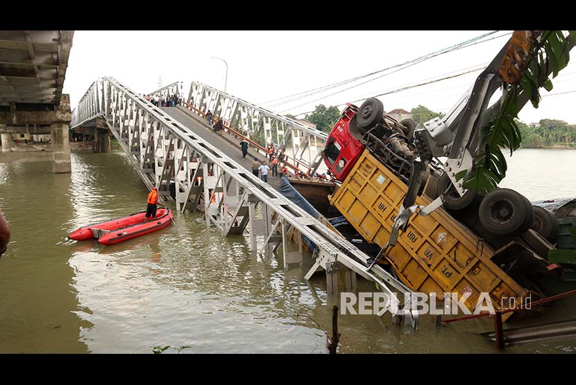 Petugas mengevakuasi truk di lokasi jembatan Widang yang runtuh, Tuban, Jawa Timur, Selasa (17/4). Sisi barat jembatan itu runtuh sekitar 50 meter dan mengakibatkan satu pengemudi truk meninggal dunia, dan melukai tiga korban lainnya, sementara tiga truk dan sebuah sepeda motor masuk ke Bengawan Solo. 