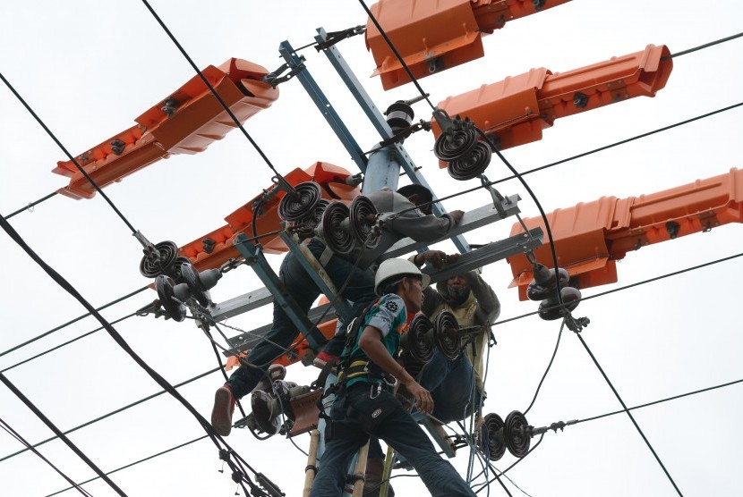 Petugas mengecek kabel jaringan listrik pada transmisi tegangan tinggi. ilustrasi