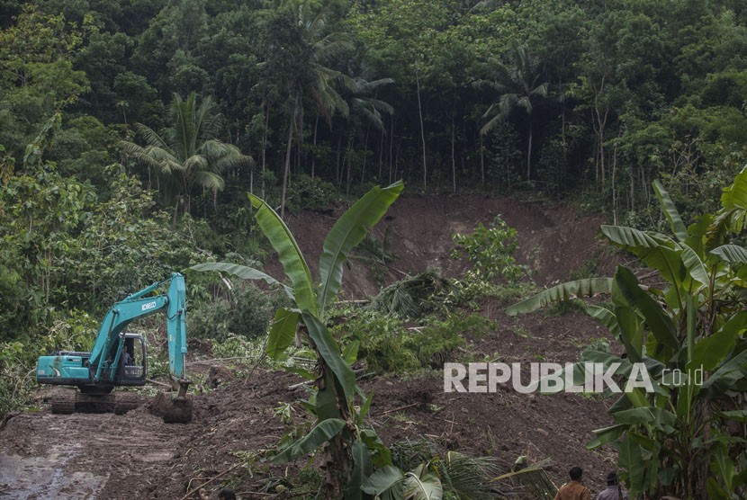 Petugas menggunakan alat berat guna membersihkan material longsor yang menutup akses jalan di kawasan di Pendoworejo, Girimulyo, Kulonprogo, DI Yogyakarta, Kamis (30/11). 