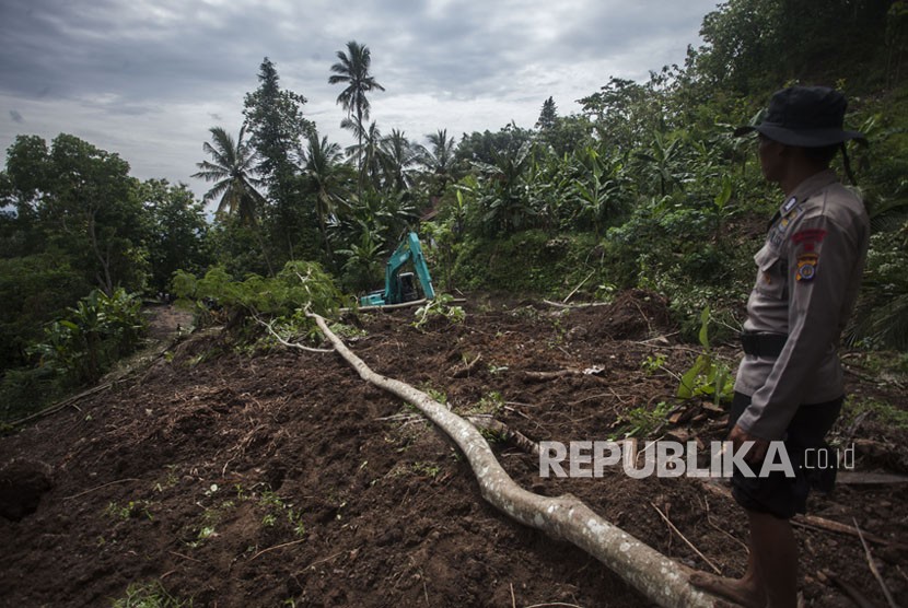 Petugas menggunakan alat berat guna membersihkan material lonsor yang menutup akses jalan di kawasan di Pendoworejo, Girimulyo, Kulonprogo, DI Yogyakarta, Kamis (30/11). 