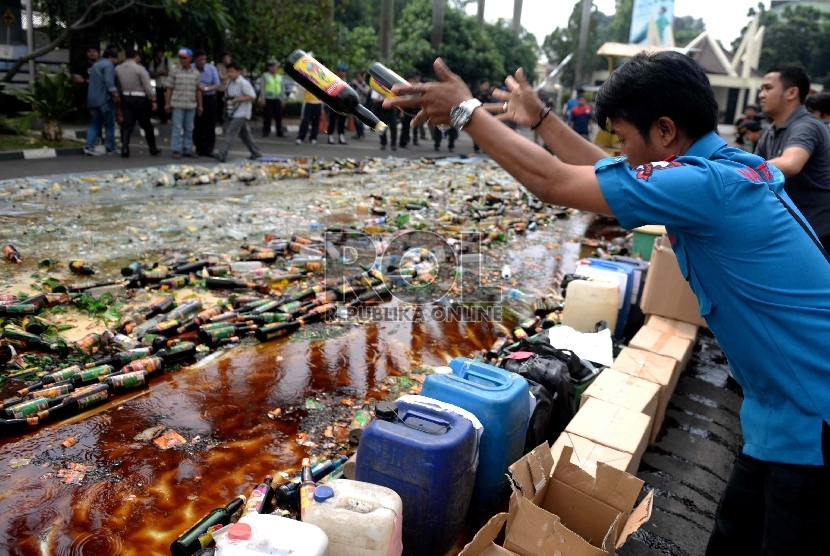 Petugas menghancurkan botol-botol miras hasil sitaan di halaman Polres Jakarta Selatan, Rabu (10/6).(Republika/Wihdan Hidayat)