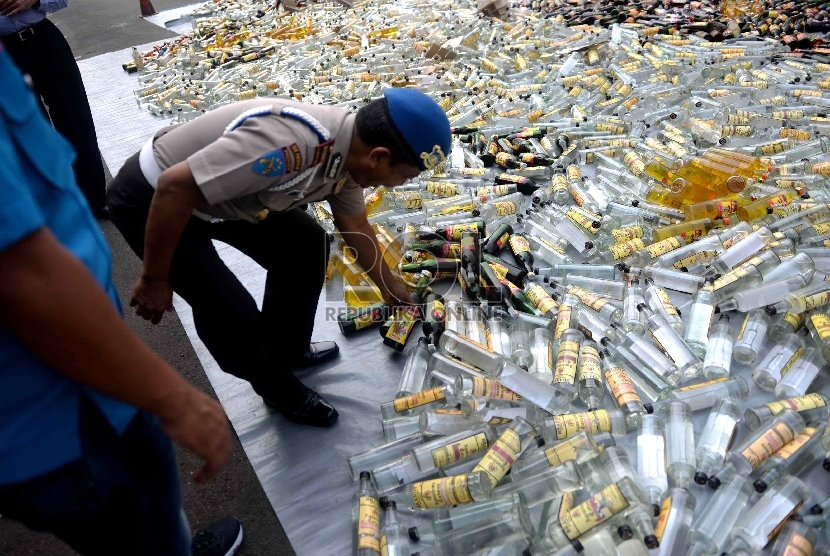 Petugas menghancurkan botol-botol miras hasil sitaan di halaman Polres Jakarta Selatan, Rabu (10/6).(Republika/Wihdan Hidayat)