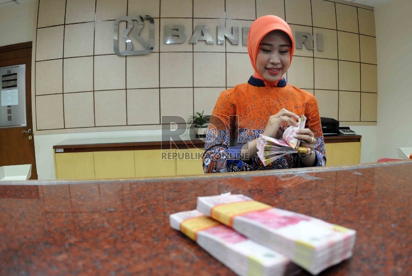  Petugas menghitung uang di banking hall Bank Rakyat Indonesia, Jakarta, Selasa (20/10).
