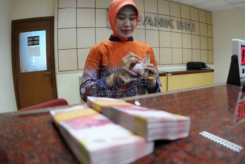  Petugas menghitung uang di banking hall Bank Rakyat Indonesia, Jakarta, Selasa (20/10).