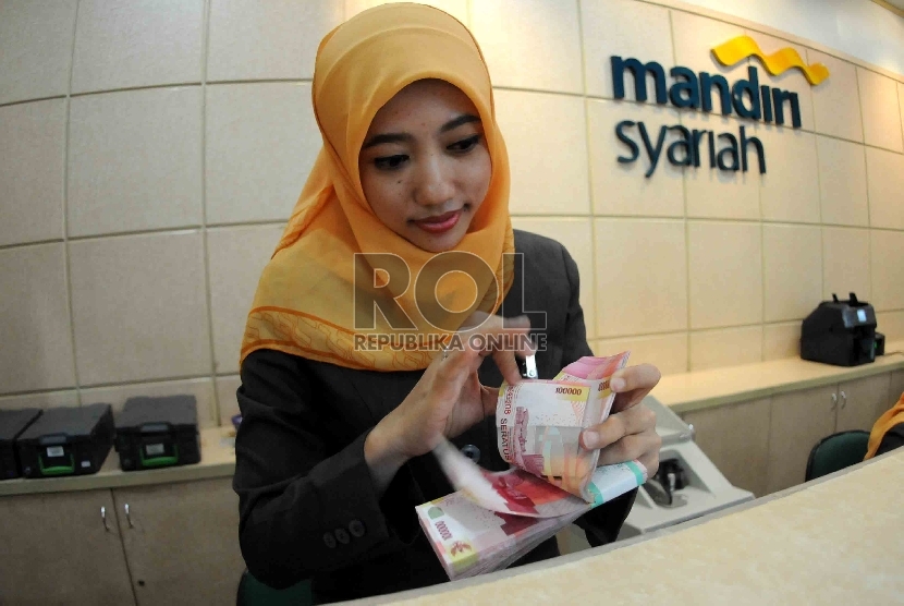  Petugas menghitung uang di banking hall Bank Syariah Mandiri, Jakarta, baru-baru ini.. 